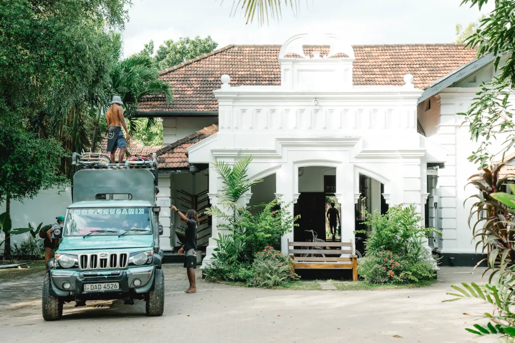 colonial style building with a blue van parked on the left-hand side.