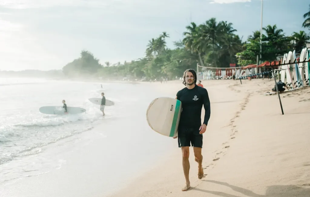 A Kima surf guest on the beach in Sri Lanka with his surf board