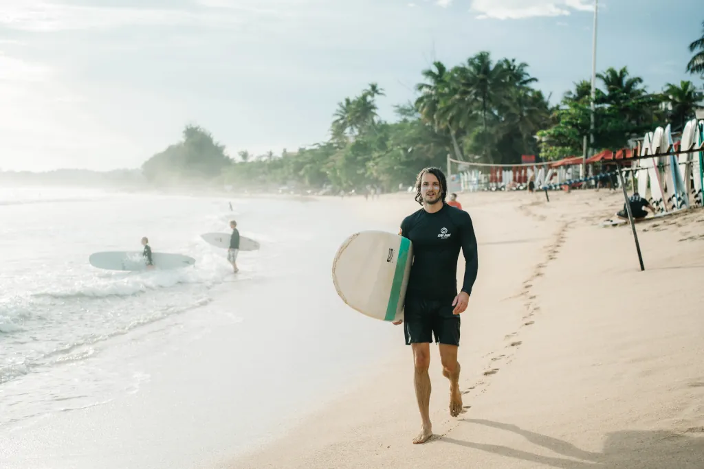 A Kima surf guest on the beach in Sri Lanka with his surf board