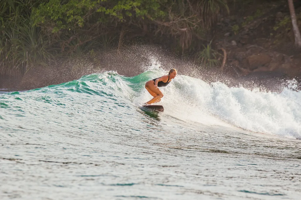 Happy healthy surfer girl surfing a wave in Sri Lanka