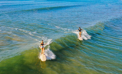 SURFER GIRLS SHARING A WAVE IN SRI LANKA
